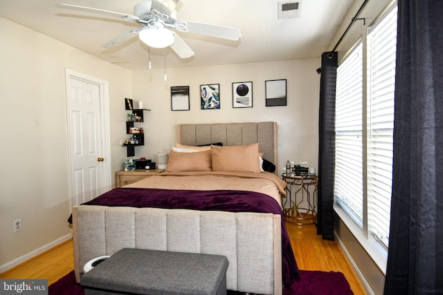 bedroom featuring ceiling fan, light hardwood / wood-style floors, and multiple windows