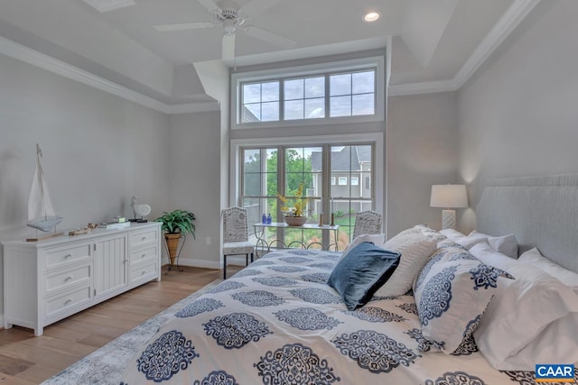 bedroom featuring ceiling fan, a raised ceiling, light hardwood / wood-style floors, and a towering ceiling