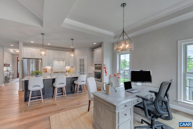 home office with a fireplace, crown molding, light hardwood / wood-style flooring, and a raised ceiling