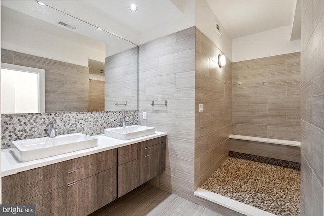 bathroom featuring decorative backsplash, vanity, and tile walls