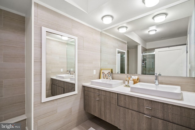 bathroom featuring vanity, a shower with shower door, and tile walls