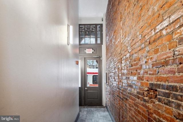 doorway to outside featuring hardwood / wood-style flooring and brick wall