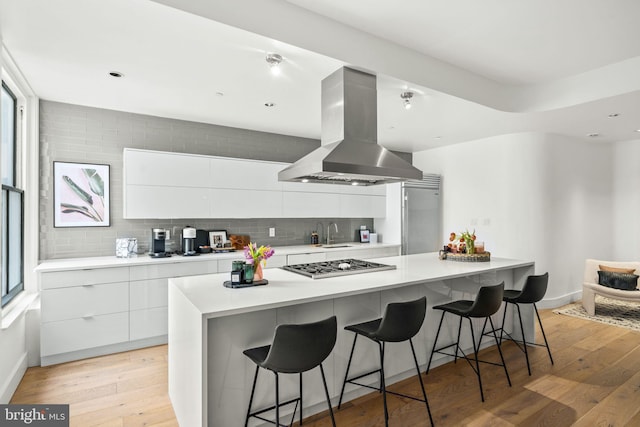 kitchen featuring white cabinets, a center island, a breakfast bar, and island exhaust hood