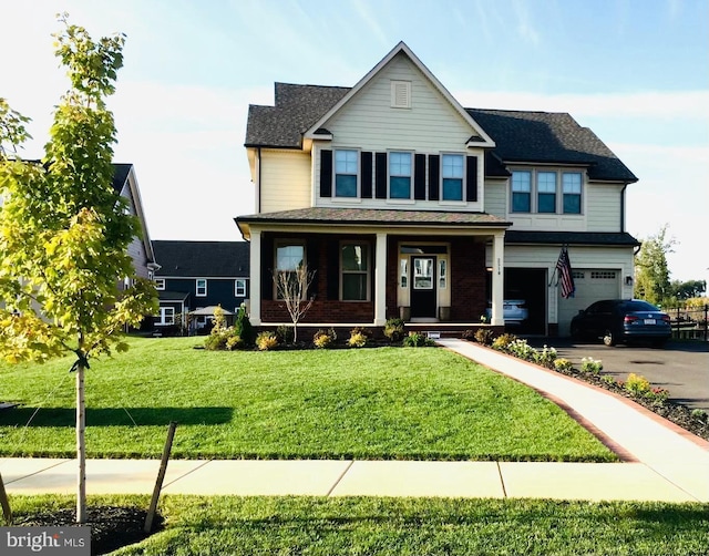 view of front of property featuring a garage, covered porch, and a front lawn