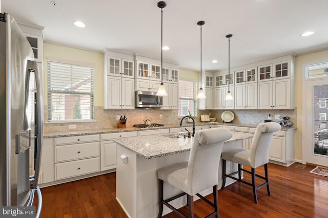 kitchen with sink, white cabinetry, appliances with stainless steel finishes, dark hardwood / wood-style flooring, and an island with sink