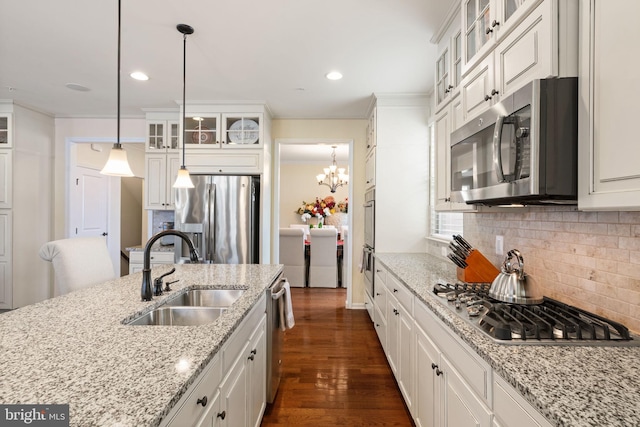 kitchen featuring pendant lighting, sink, white cabinets, light stone counters, and stainless steel appliances