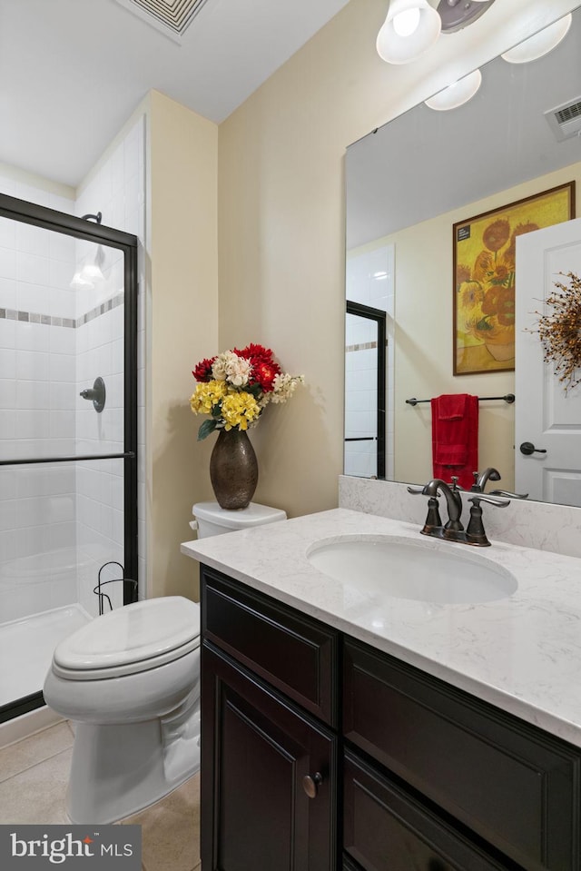 bathroom featuring tile patterned floors, toilet, a shower with shower door, and vanity