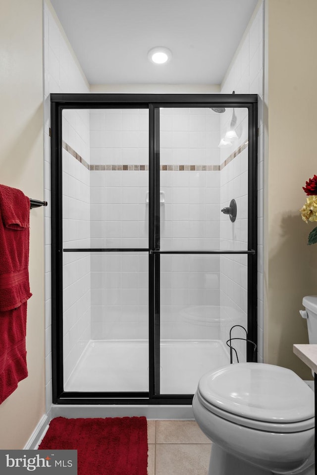 bathroom with tile patterned floors, toilet, and an enclosed shower