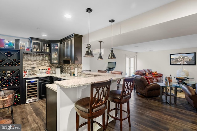 kitchen featuring hanging light fixtures, a kitchen breakfast bar, kitchen peninsula, beverage cooler, and decorative backsplash