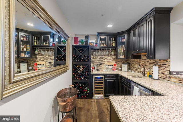 bar with sink, backsplash, wine cooler, light stone counters, and dark wood-type flooring