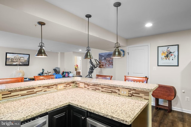 kitchen featuring pendant lighting, light stone counters, dark hardwood / wood-style flooring, and stainless steel dishwasher