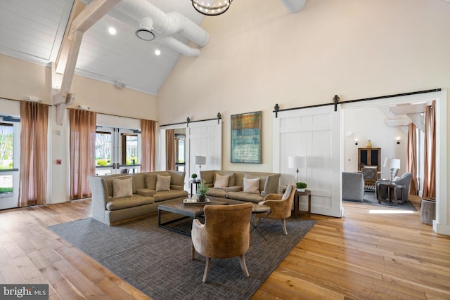 living room featuring light hardwood / wood-style flooring, high vaulted ceiling, a barn door, and french doors