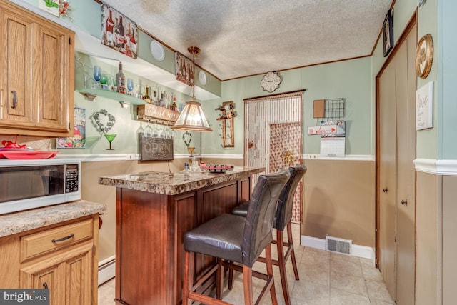 kitchen featuring a breakfast bar, hanging light fixtures, ornamental molding, baseboard heating, and a textured ceiling