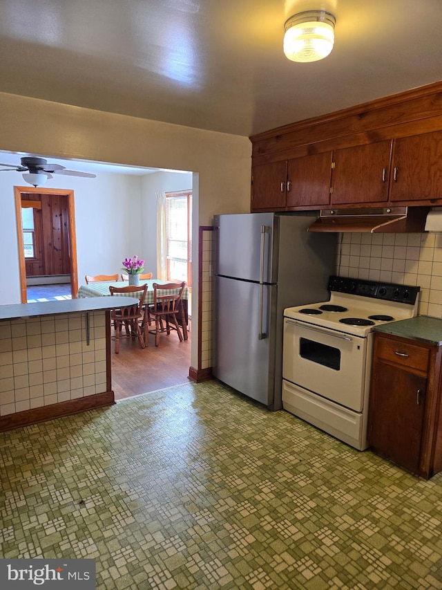 kitchen featuring white electric stove, decorative backsplash, a ceiling fan, dark countertops, and under cabinet range hood