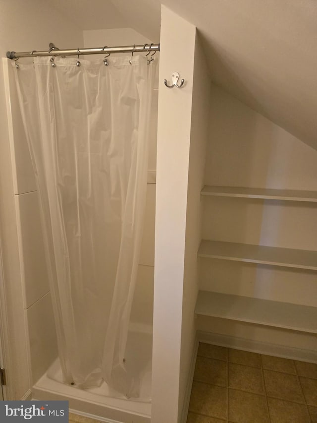 bathroom featuring tile patterned flooring, vaulted ceiling, and a shower with shower curtain