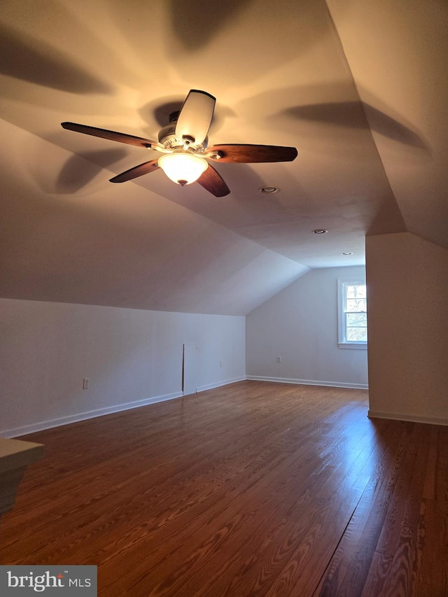 bonus room with vaulted ceiling, dark wood-type flooring, a ceiling fan, and baseboards