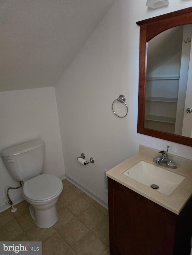 bathroom featuring toilet, baseboards, vaulted ceiling, and vanity