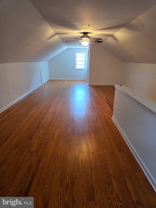 additional living space featuring lofted ceiling, ceiling fan, dark wood-style flooring, and baseboards