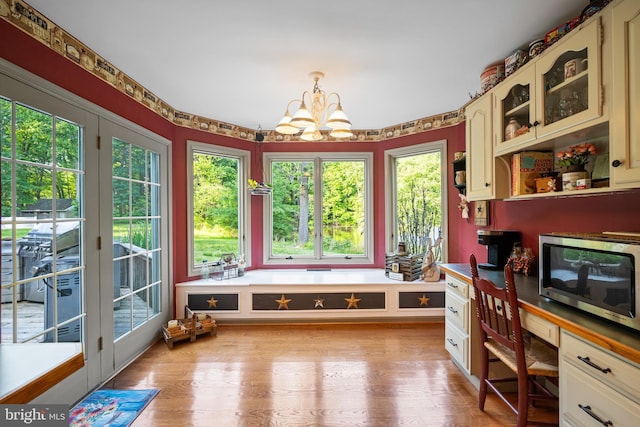 office area featuring light wood-type flooring, a notable chandelier, a wealth of natural light, and built in desk