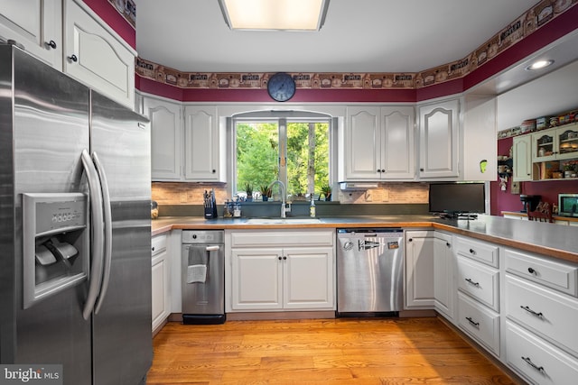 kitchen featuring sink, white cabinetry, light hardwood / wood-style floors, decorative backsplash, and stainless steel appliances