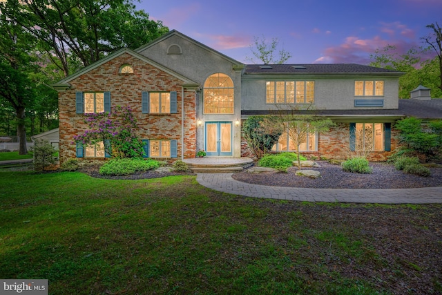 view of front facade with a lawn and french doors