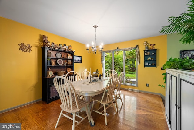 dining space featuring hardwood / wood-style flooring and an inviting chandelier