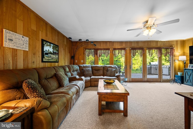 living room featuring ceiling fan, light carpet, and wooden walls