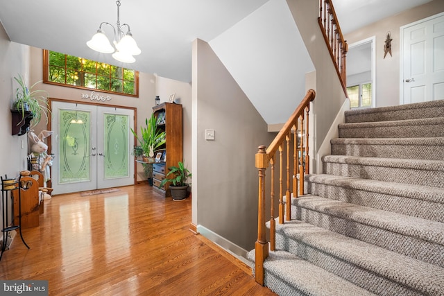 entrance foyer featuring wood-type flooring, an inviting chandelier, and french doors