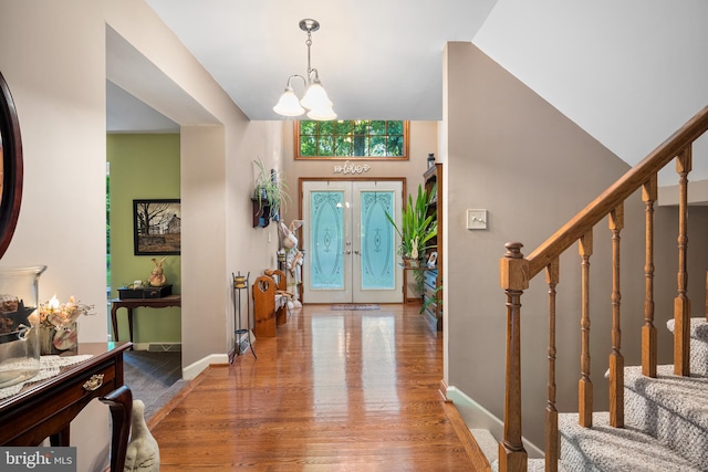 entrance foyer with wood-type flooring, a notable chandelier, and french doors