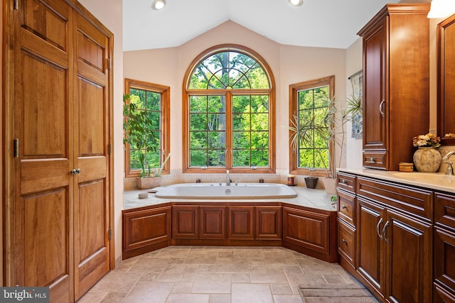 bathroom with a tub to relax in, vaulted ceiling, and vanity