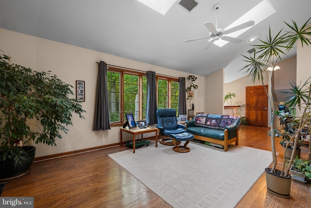 living room with ceiling fan, lofted ceiling with skylight, and wood-type flooring