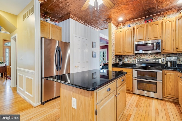 kitchen with light wood-type flooring, stainless steel appliances, an ornate ceiling, and a center island