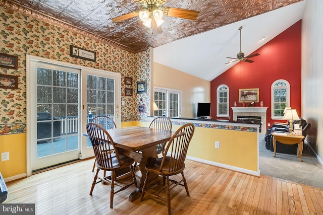 dining area with ceiling fan, baseboards, hardwood / wood-style flooring, a glass covered fireplace, and an ornate ceiling