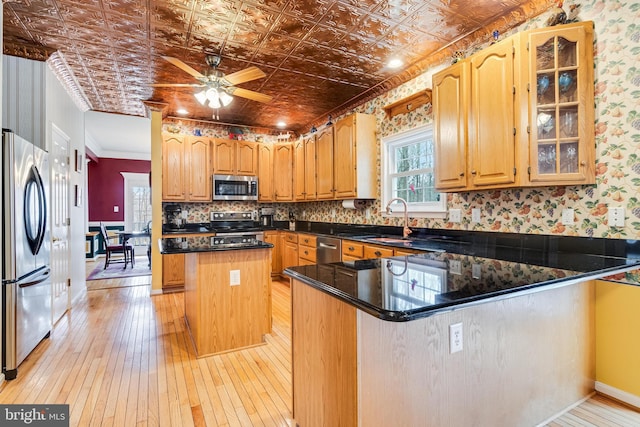 kitchen with a kitchen island, appliances with stainless steel finishes, a peninsula, an ornate ceiling, and a sink