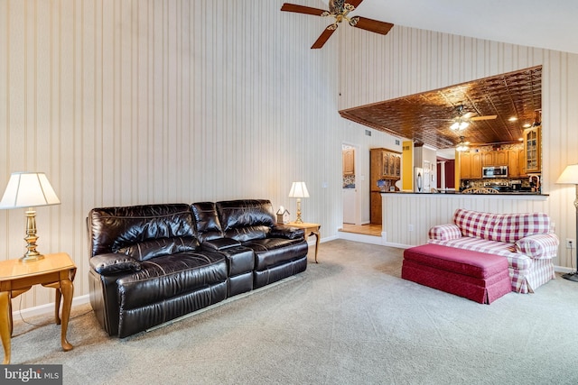 carpeted living room with a ceiling fan, baseboards, and high vaulted ceiling