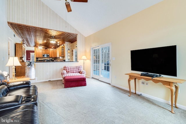 living area featuring light carpet, a ceiling fan, baseboards, and high vaulted ceiling