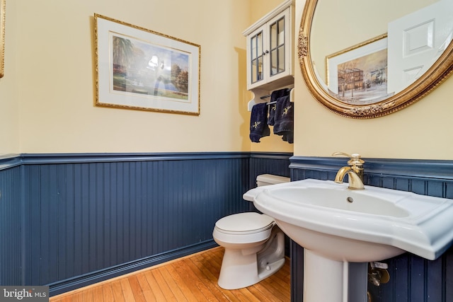 bathroom featuring a sink, a wainscoted wall, toilet, and hardwood / wood-style floors