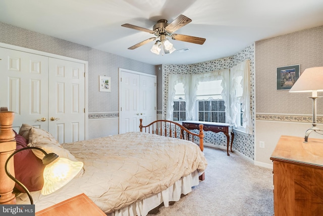 bedroom featuring visible vents, two closets, wallpapered walls, ceiling fan, and carpet flooring