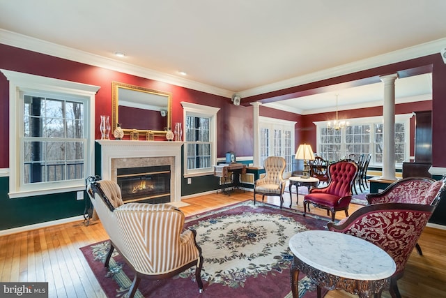 living area featuring a fireplace with flush hearth, wood-type flooring, and ornate columns