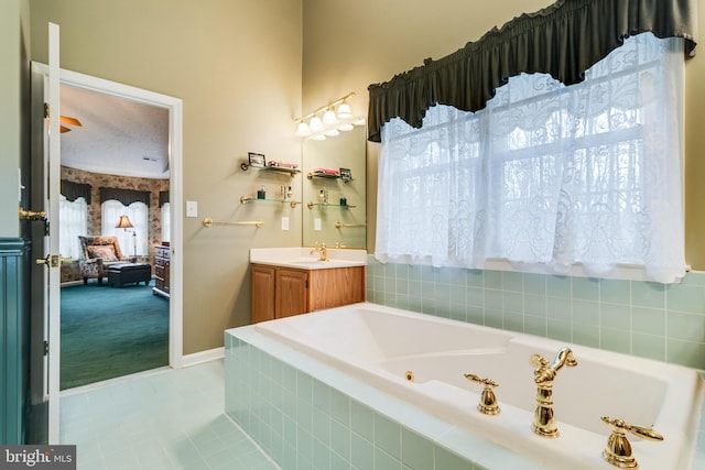 bathroom with a textured ceiling, a tub with jets, tile patterned flooring, baseboards, and vanity