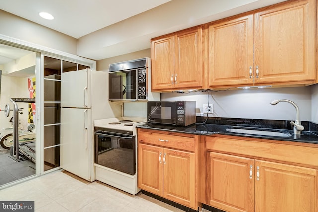 kitchen with white appliances, dark stone counters, and a sink