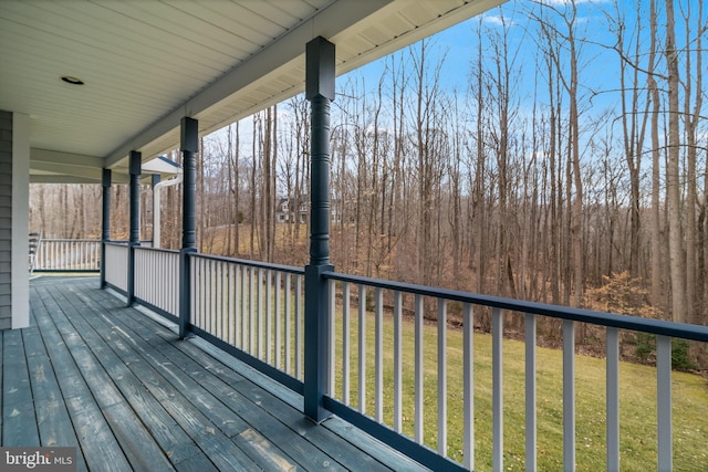 deck featuring a lawn and a wooded view