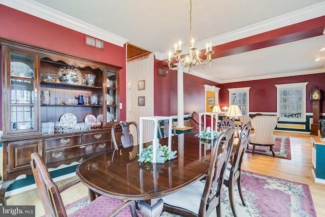 dining area with visible vents, ornamental molding, an inviting chandelier, and wood finished floors