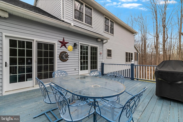 wooden terrace with outdoor dining area and a grill