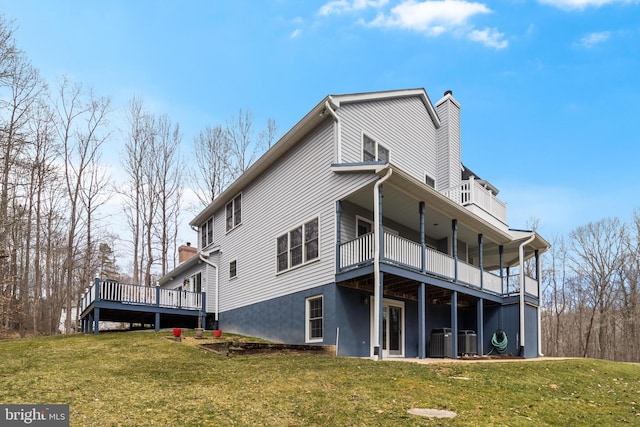 back of house featuring central AC unit, a lawn, and a chimney