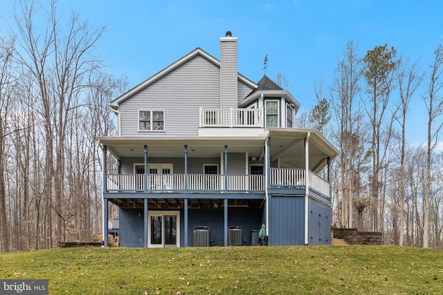 back of property with a yard, a balcony, and central AC unit