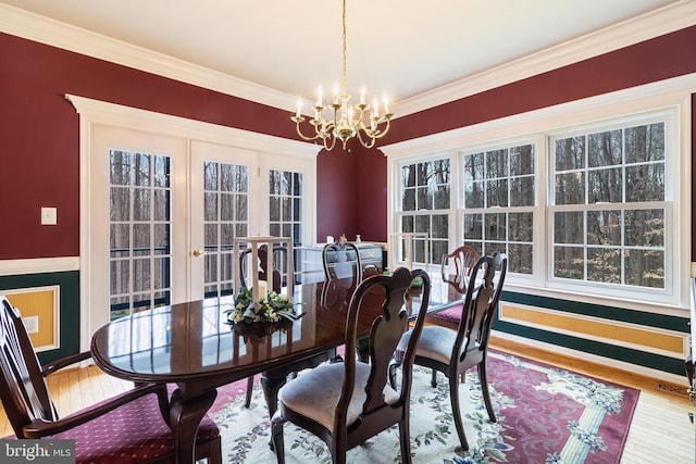 dining area with a notable chandelier, ornamental molding, and wood finished floors