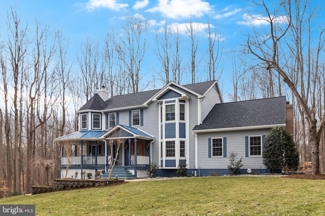 view of front of house with covered porch, a chimney, a front yard, and a shingled roof