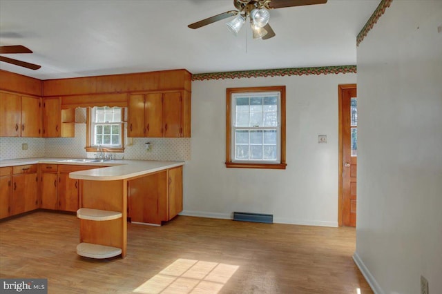 kitchen featuring light wood-type flooring, backsplash, ceiling fan, and kitchen peninsula