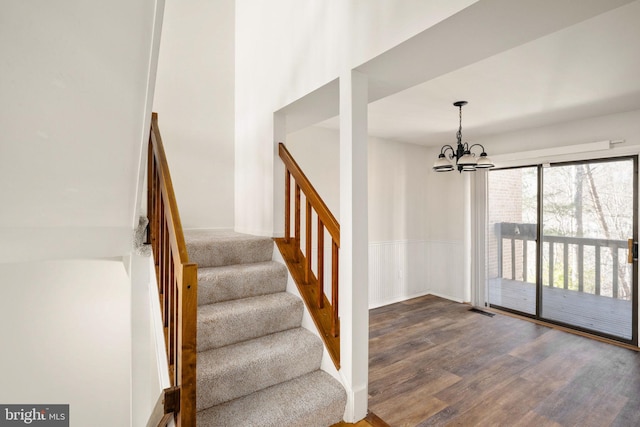 staircase with an inviting chandelier and hardwood / wood-style floors